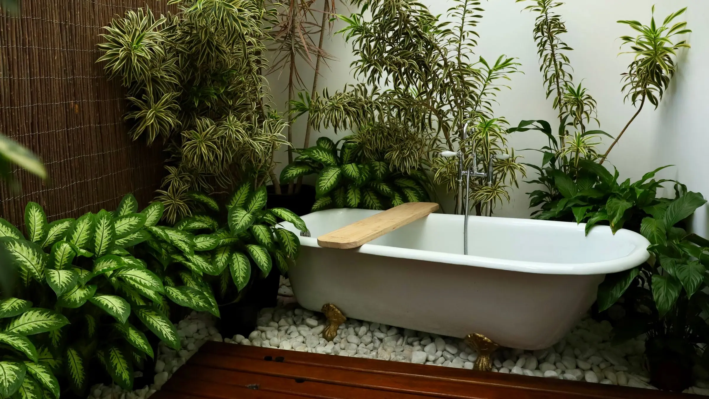 Freestanding bathtub in an open-air villa bathroom with plants