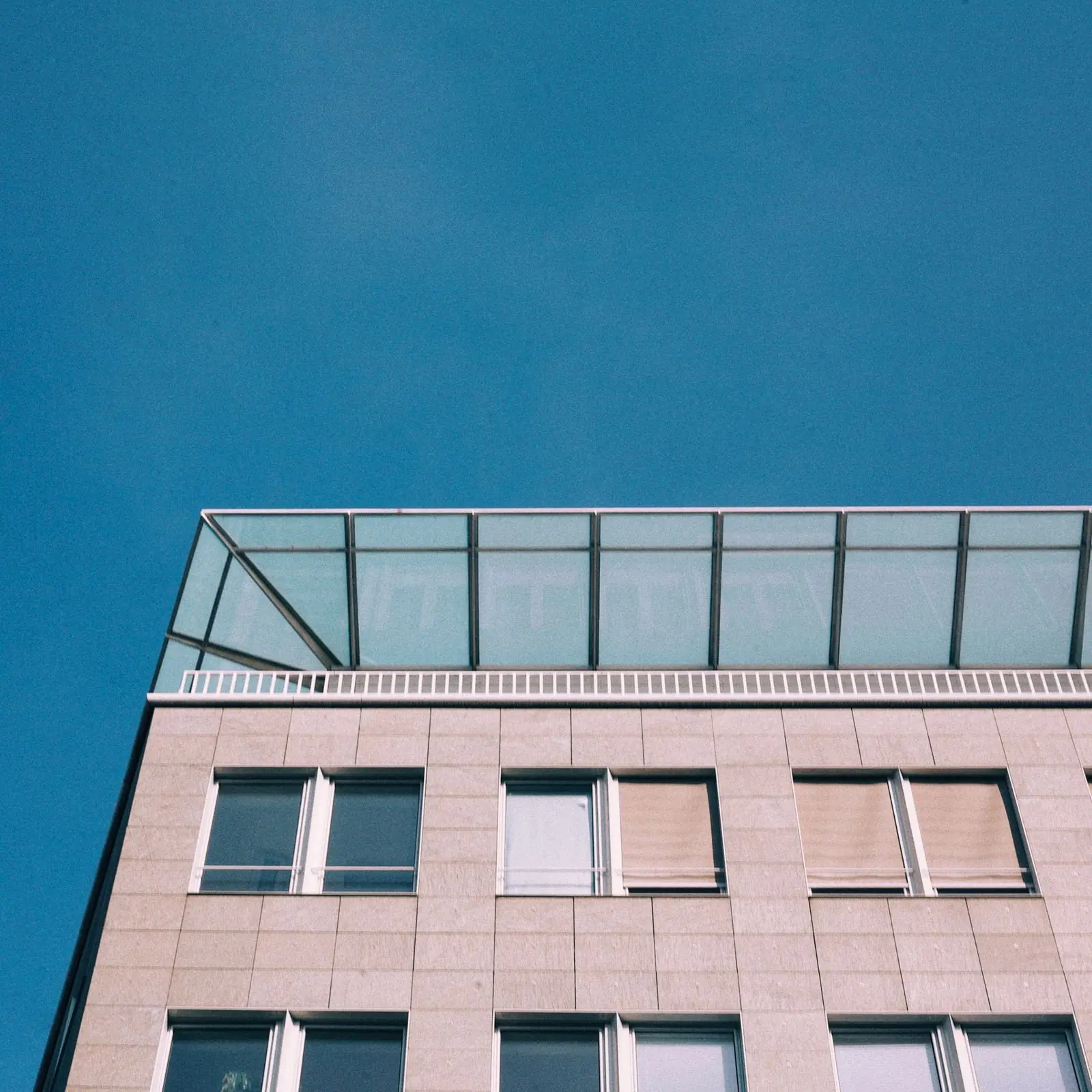 Corner of a multi-storey office building against a clear blue sky
