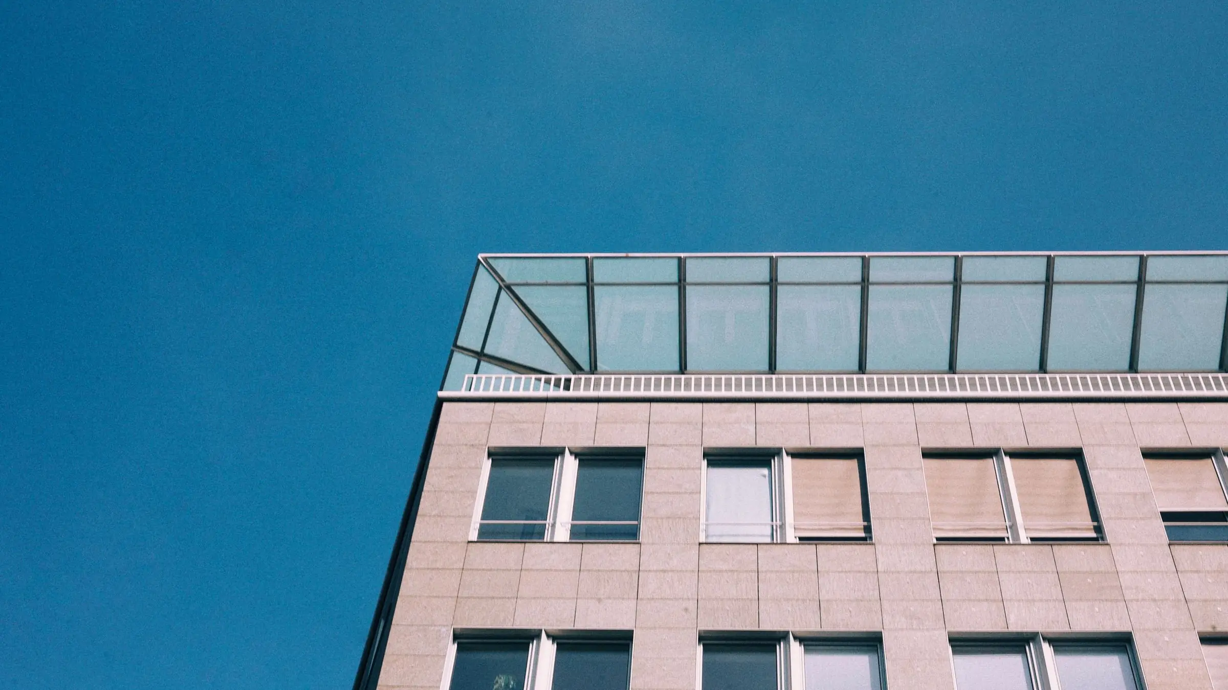 Corner of a multi-storey office building against a clear blue sky