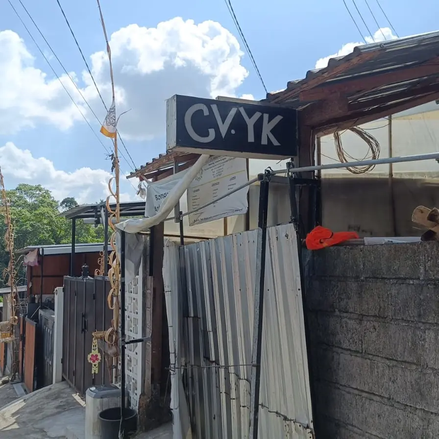 The CV.YK sign above our office gate in Nyitdah, with penjor bamboo poles along the lane