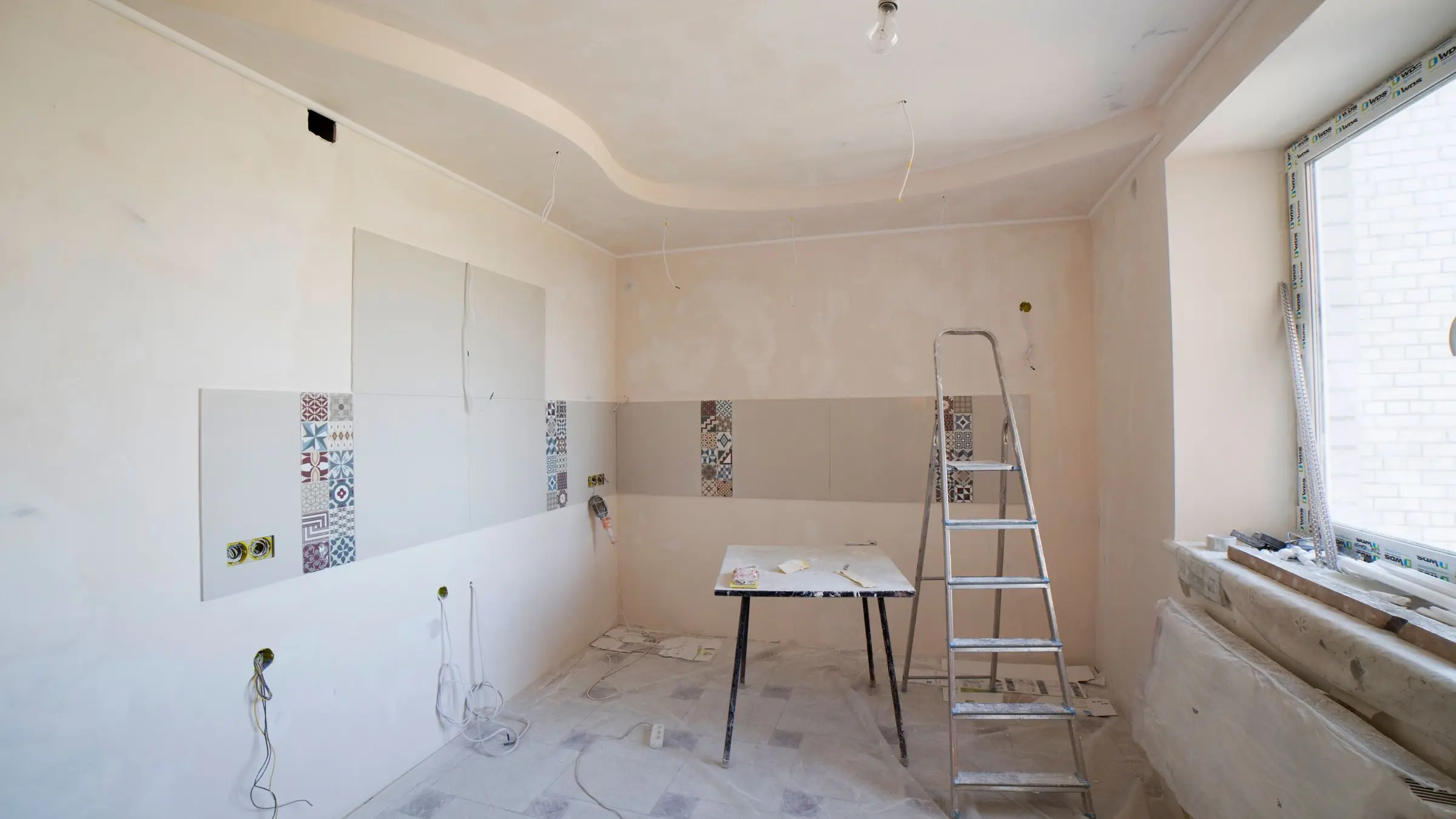 Room under renovation with fresh plaster, tile samples and a stepladder
