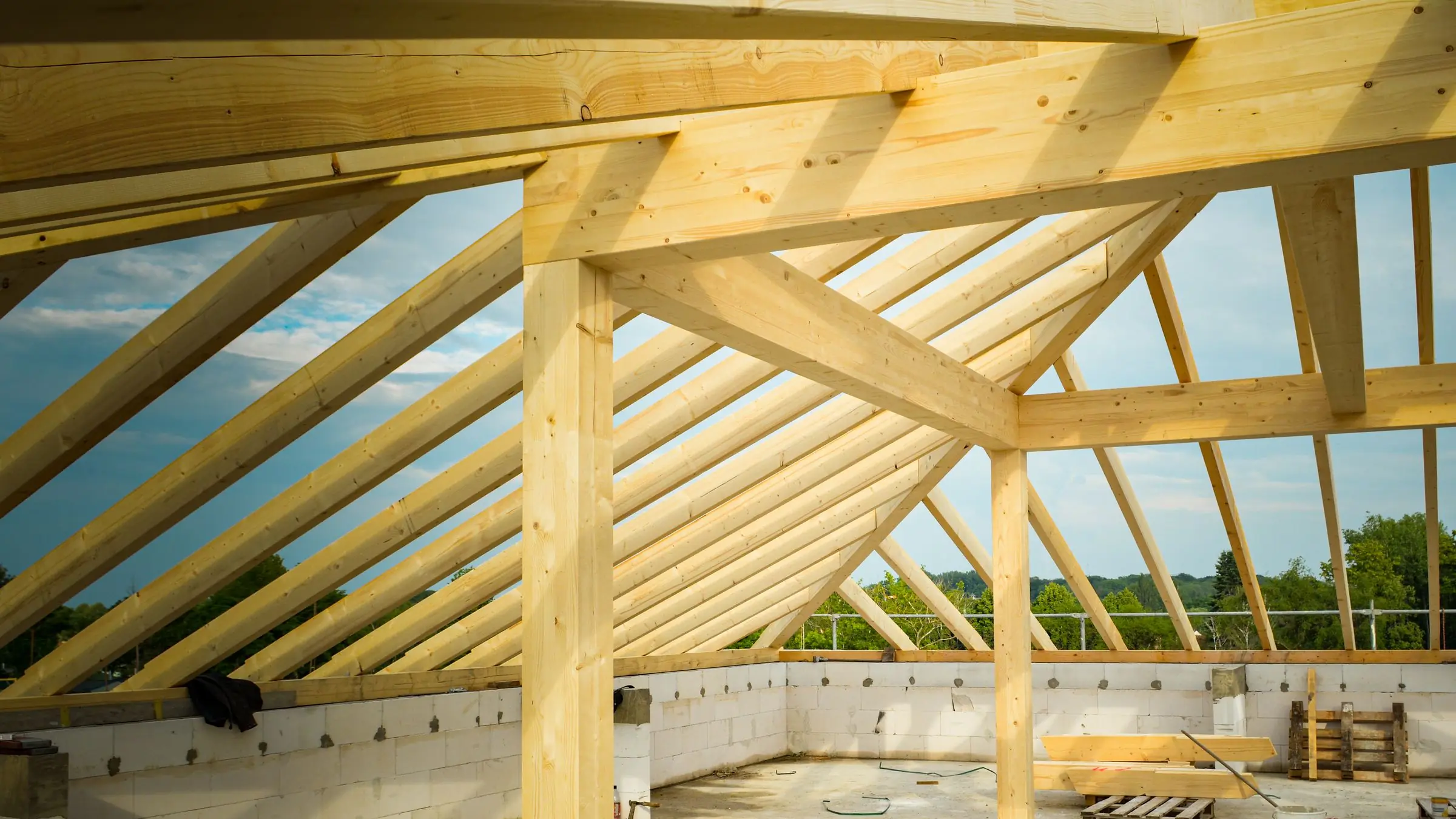 Timber roof frame under construction against a blue sky