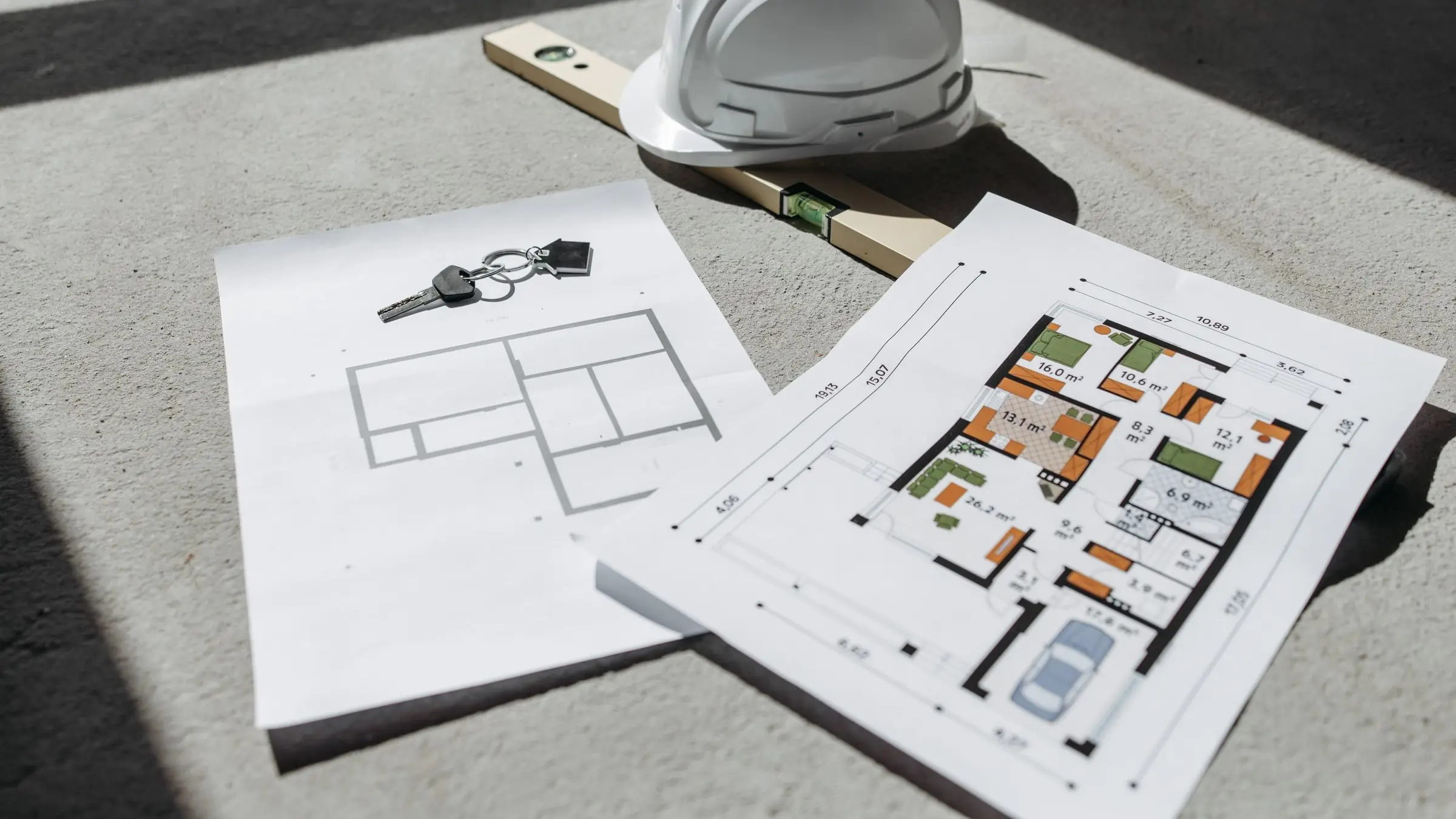 Floor plans, a safety helmet and a spirit level on a concrete floor